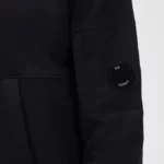 Proposé dans une coupe droite, ce sweatshirt CP Company pour homme présente une poche kangourou sur le devant, une capuche réglable par cordons de serrage