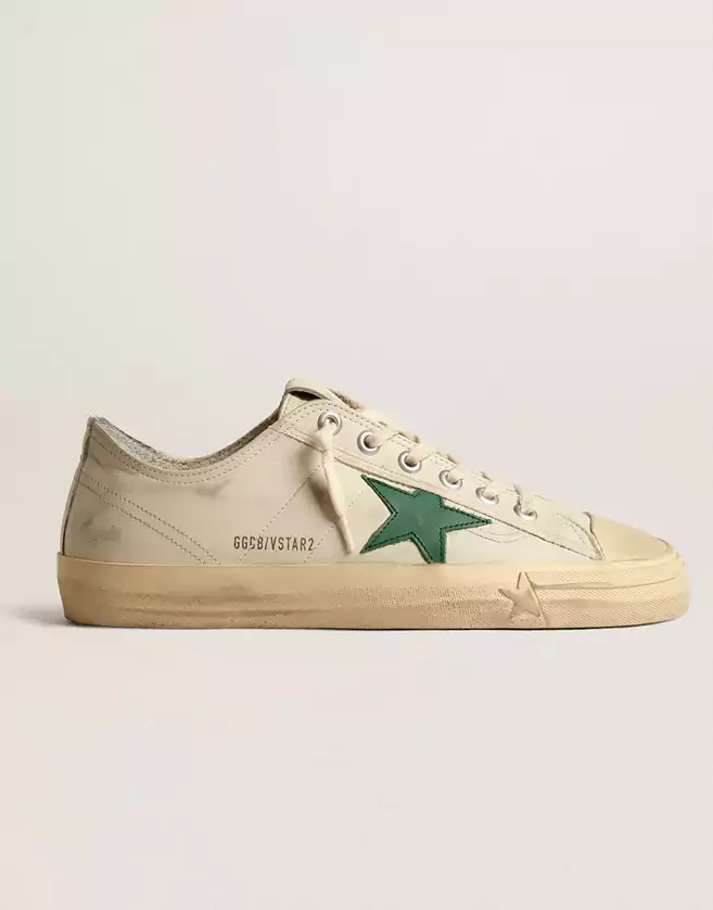 Sneakers Golden Goose dotées d’une tige en cuir brillant blanc cassé, ce modèle se distingue par une étoile en cuir vert. Les lacets beiges apportent la touche finale.