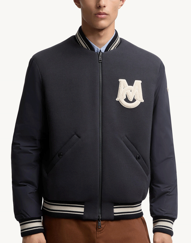 Cette veste Moncler inspirée du style universitaire revisite le bomber classique pour homme dans une version réversible rembourrée de duvet.